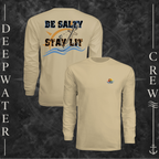 Sand Deepwater Crew Co. Be Salty, Stay Lit UPF 44+ long-sleeve performance shirt showing front and back views with cross, sunset, and wave chest crest with DC logo and Matthew 5:13–14 anchor-and-wave back graphic.