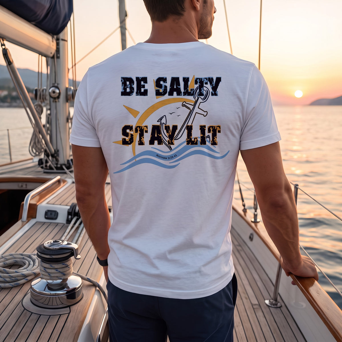 Man wearing a White Deepwater Crew Co. Be Salty, Stay Lit T-shirt, back view aboard a sailboat at sunset.