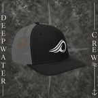 Deepwater Crew Co. black and gray Richardson 112 trucker hat with white embroidered wave logo, breathable mesh back, and structured six-panel design with snapback closure.