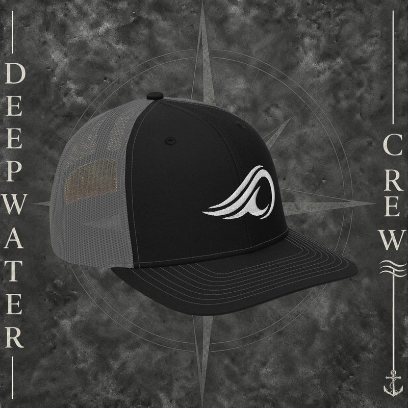 Deepwater Crew Co. black and gray Richardson 112 trucker hat with white embroidered wave logo, breathable mesh back, and structured six-panel design with snapback closure.