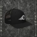 Deepwater Crew Co. black Richardson 112 trucker hat with white embroidered wave logo, breathable mesh back, and structured six-panel design with snapback closure.