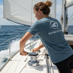 Woman wearing a blue Deepwater Crew Co. cotton t-shirt with a white logo on the back while sailing on a boat.