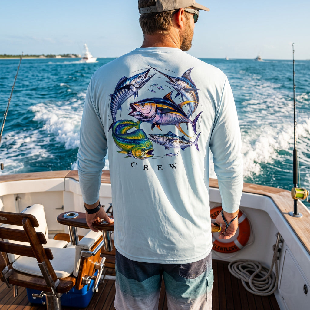Man wearing a pastel blue Deepwater Crew Co. Bluewater Strike UPF 44+ long-sleeve performance shirt, back view with colorful pelagic game fish collage and Deepwater Crew lettering while offshore fishing.