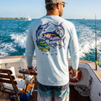Man wearing a pastel blue Deepwater Crew Co. Bluewater Strike UPF 44+ long-sleeve performance shirt, back view with colorful pelagic game fish collage and Deepwater Crew lettering while offshore fishing.