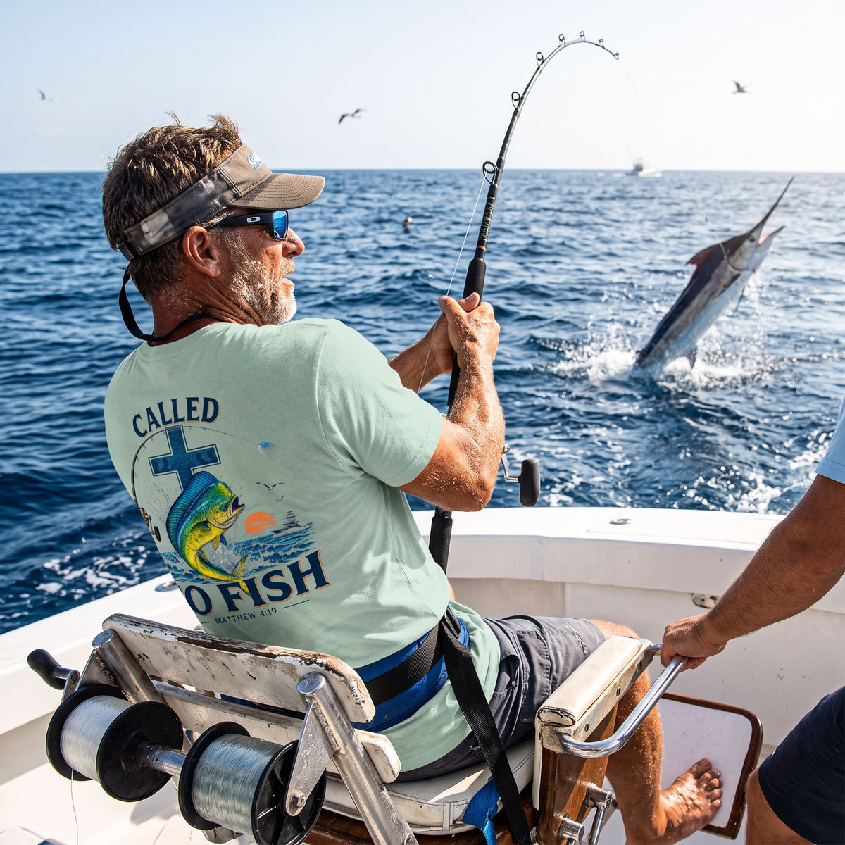 Man wearing a Dusty Blue Deepwater Crew Co. Called to Fish T-shirt, back view while offshore fishing from a boat.