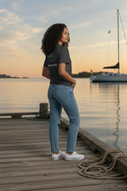 Deepwater Crew Co. model wearing a charcoal grey crew neck t-shirt with a back graphic on a wooden dock at sunset.