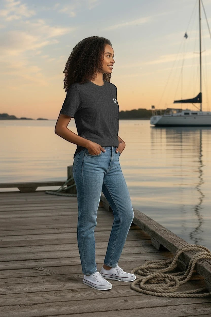 Woman wearing a Deepwater Crew Co. charcoal grey cotton crew neck t-shirt standing on a wooden dock at sunset.