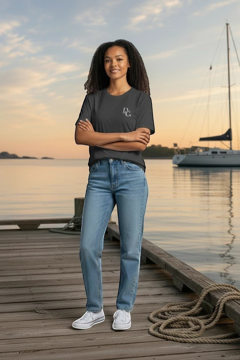 Woman wearing a Deepwater Crew Co. charcoal grey cotton crew neck t-shirt with a small logo on a wooden dock at sunset.