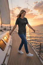 Woman wearing a Deepwater Crew Co. charcoal grey cotton t-shirt with a small logo on a sailboat at sunset