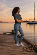 Deepwater Crew Co. charcoal grey cotton crew neck t-shirt worn by a woman on a wooden dock at sunset.