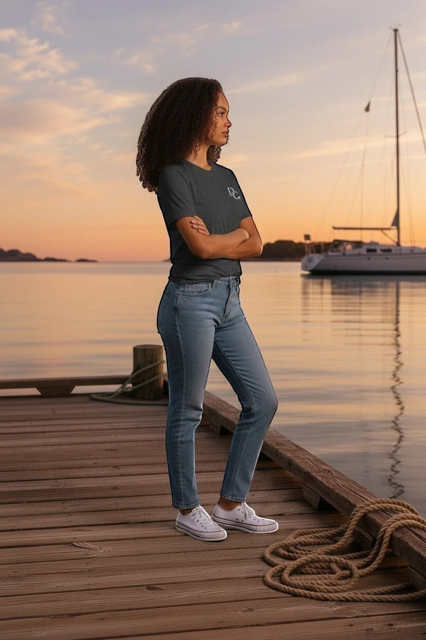 Deepwater Crew Co. charcoal grey cotton crew neck t-shirt worn by a woman on a wooden dock at sunset.