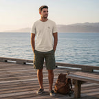 Deepwater Crew Co. man wearing a cream cotton crew neck t-shirt with a small logo on a wooden pier by the ocean.