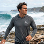 Deepwater Crew Co. dark grey performance long-sleeve hooded shirt with UPF protection worn by a man at the beach.