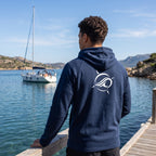 Deepwater Crew Co. dark blue performance hoodie with white logo on back, worn by a man on a wooden dock by a sailboat.