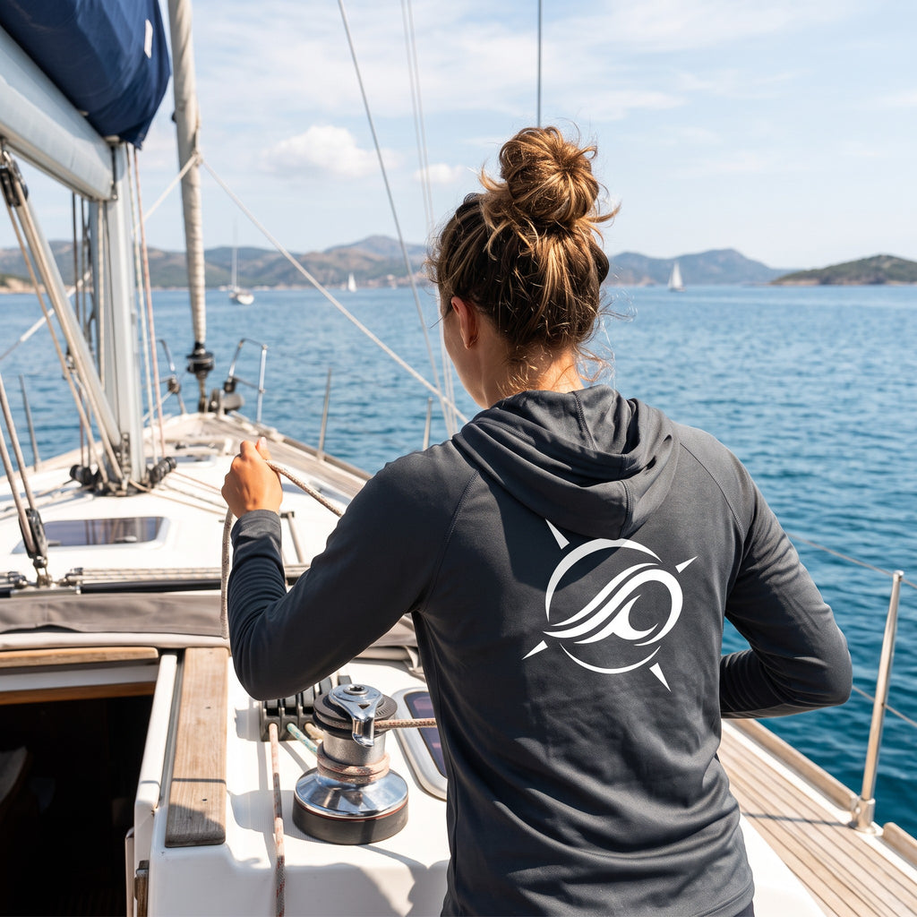 Deepwater Crew Co. dark performance sun hoodie with white logo on back worn by woman sailing on a boat