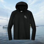 Deepwater Crew Co. dark performance hoodie with UPF 44+ sun protection and white logo on chest against water background
