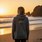 Deepwater Crew Co. dark grey performance UPF hoodie with back logo, worn by a person on the beach at sunset.