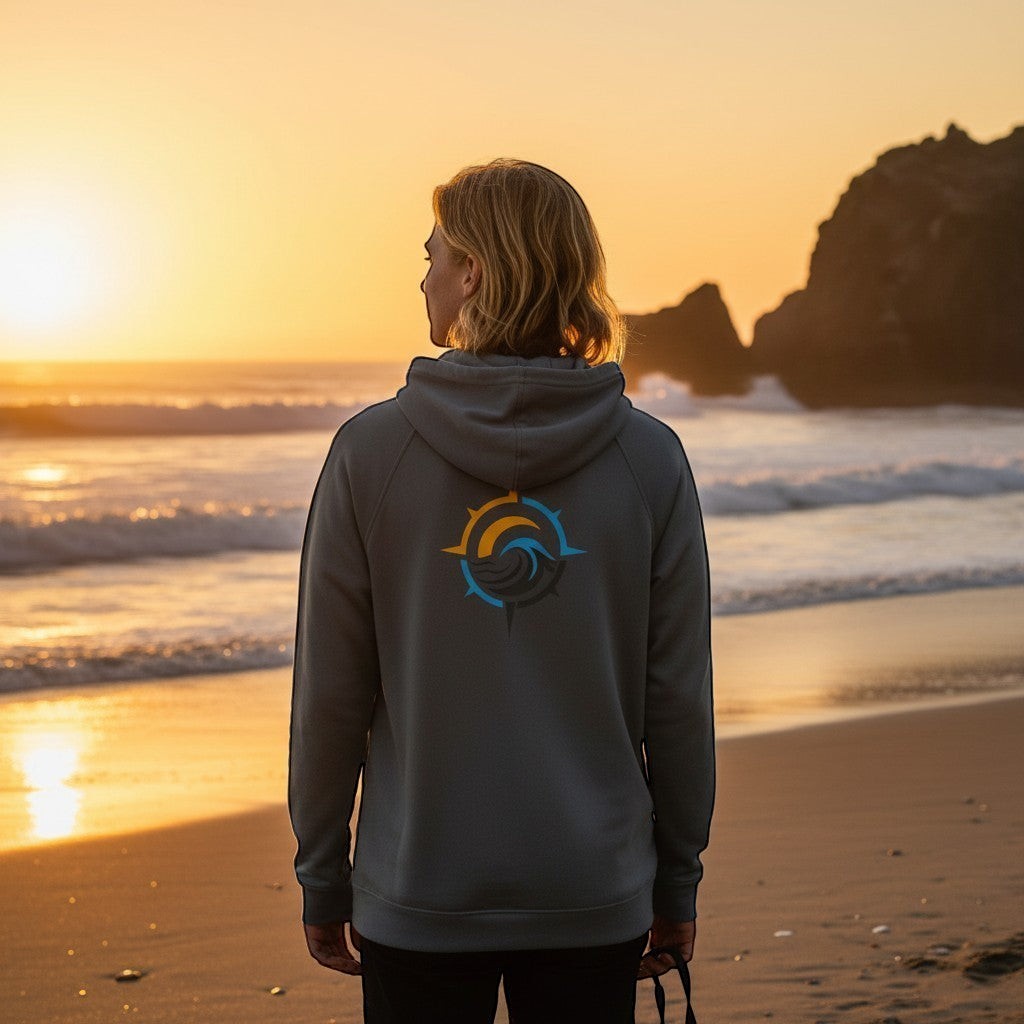 Deepwater Crew Co. dark grey performance UPF hoodie with back logo, worn by a person on the beach at sunset.