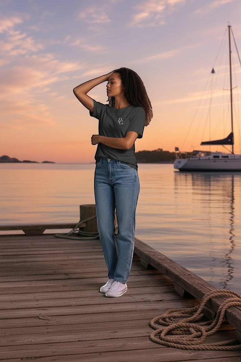Deepwater Crew Co. model wearing a dark grey cotton crew neck t-shirt with a small logo on a wooden pier at sunset.