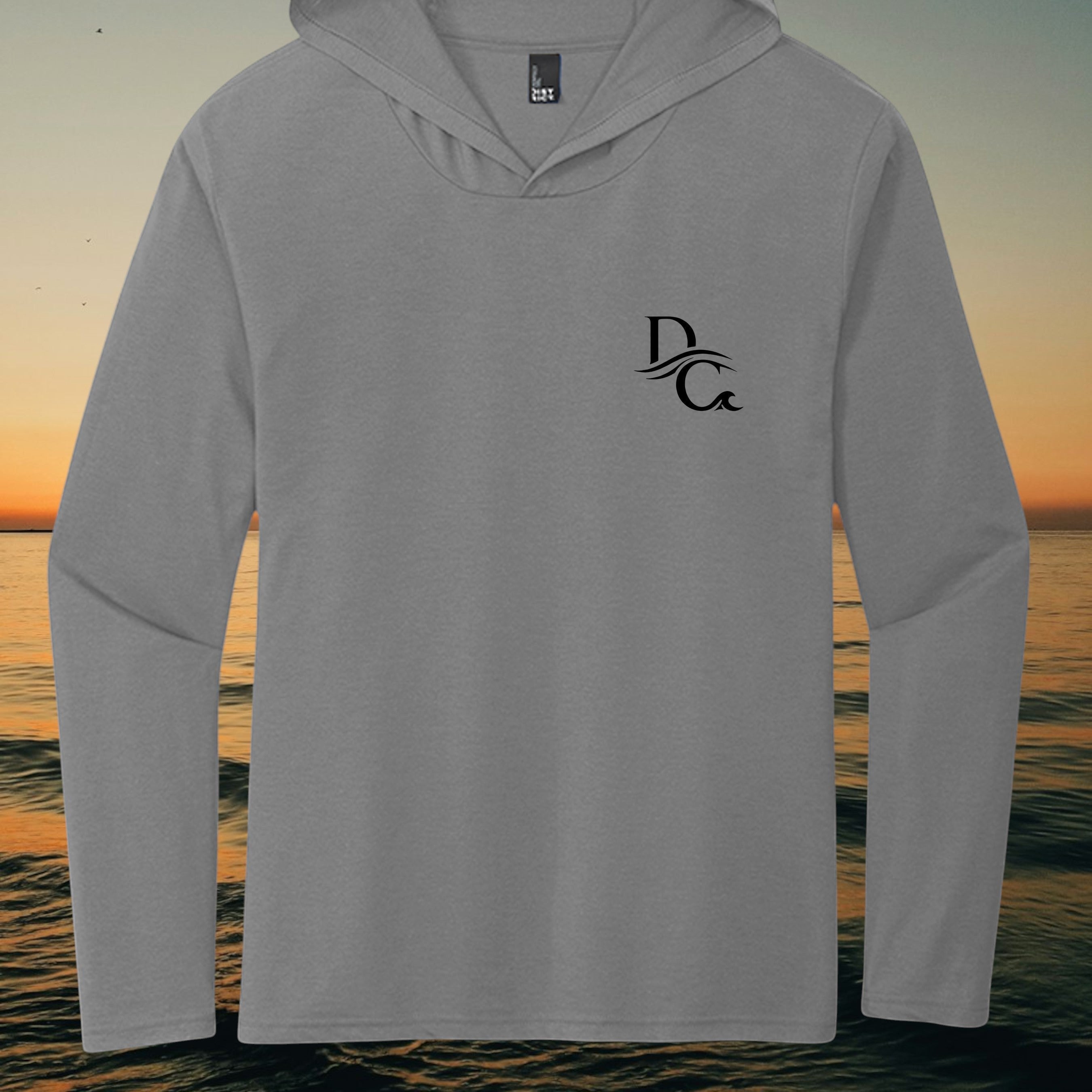 Deepwater Crew Co. grey tri-blend long sleeve hoodie tee with a black chest logo against a coastal sunset background.