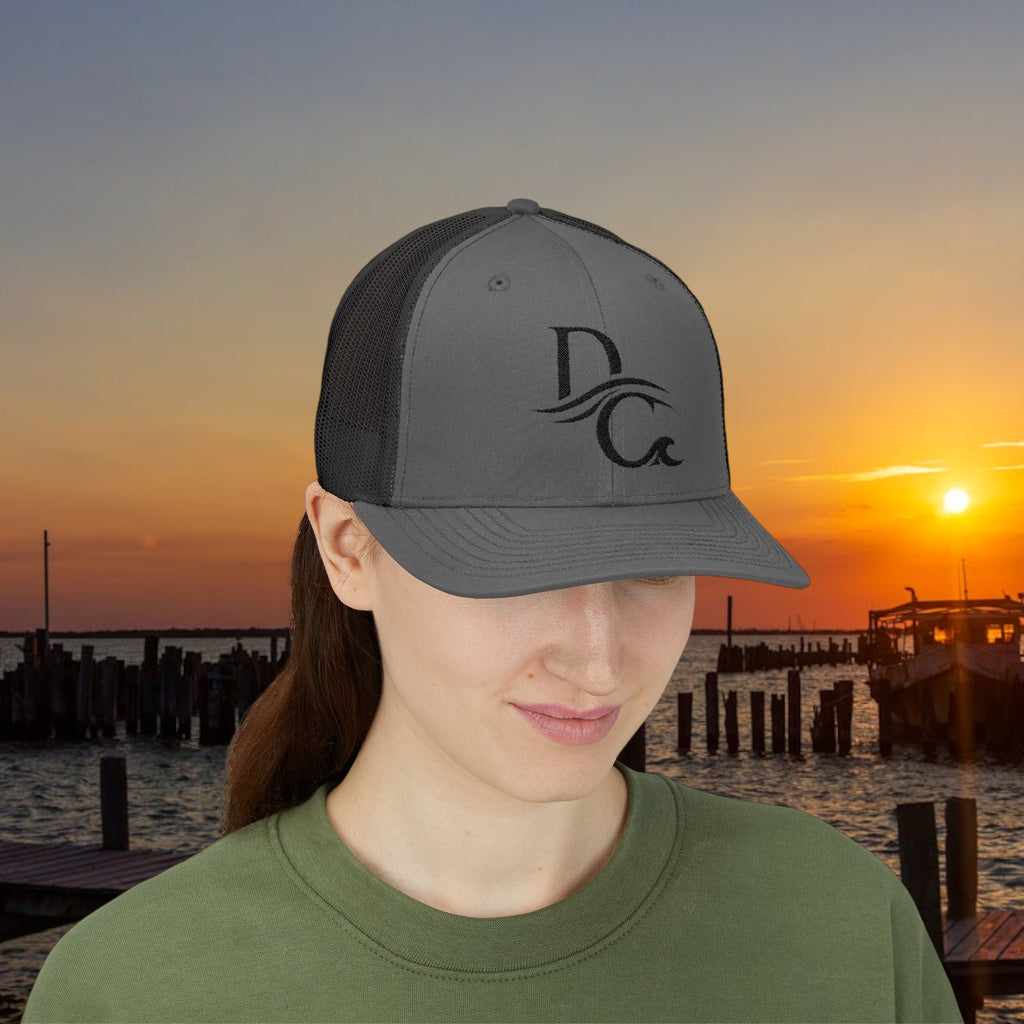 Deepwater Crew Co. dark grey trucker hat with black mesh back and embroidered DC logo. Structured mid-profile with snapback closure.