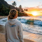 Deepwater Crew Co. hooded long sleeve tee with blue wave graphic on back, worn by person on beach at sunset.