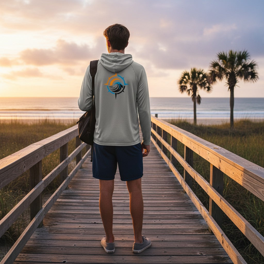 Deepwater Crew Co. light grey performance UV hoodie with back logo, worn by a man on a beach boardwalk at sunset.