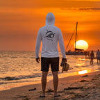 Deepwater Crew Co. light performance sun hoodie with logo on back, worn by a man on a beach at sunset.