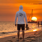 Deepwater Crew Co. light performance sun hoodie with logo on back, worn by a man on a beach at sunset.