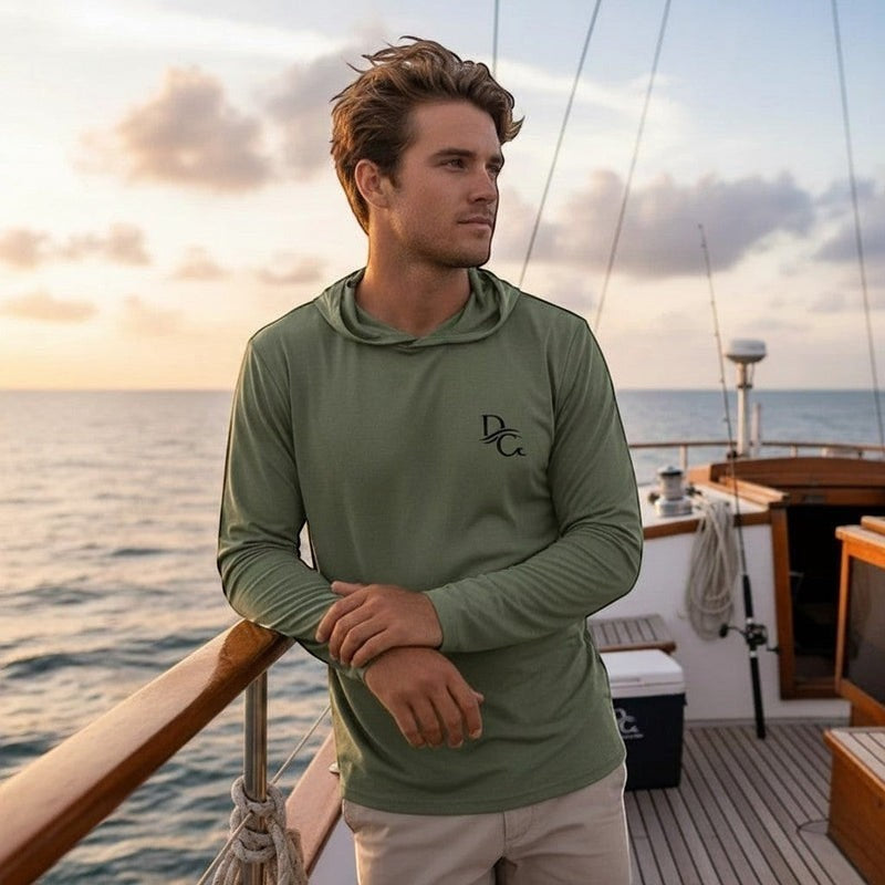 Deepwater Crew Co. man wearing a sage green long sleeve hooded tee with chest logo on a boat at sunset
