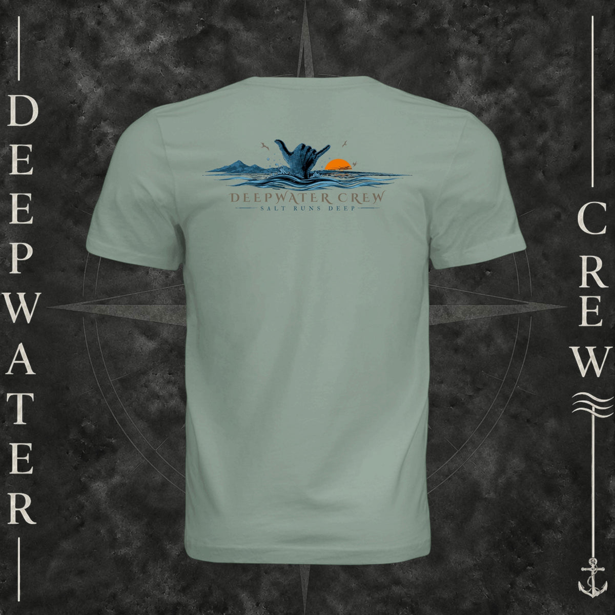 Sage Deepwater Crew Co. Salt Runs Deep crewneck T-shirt, back view with shaka hand, ocean waves, distant mountains, orange sunset, seabirds, and “Salt Runs Deep” lettering.