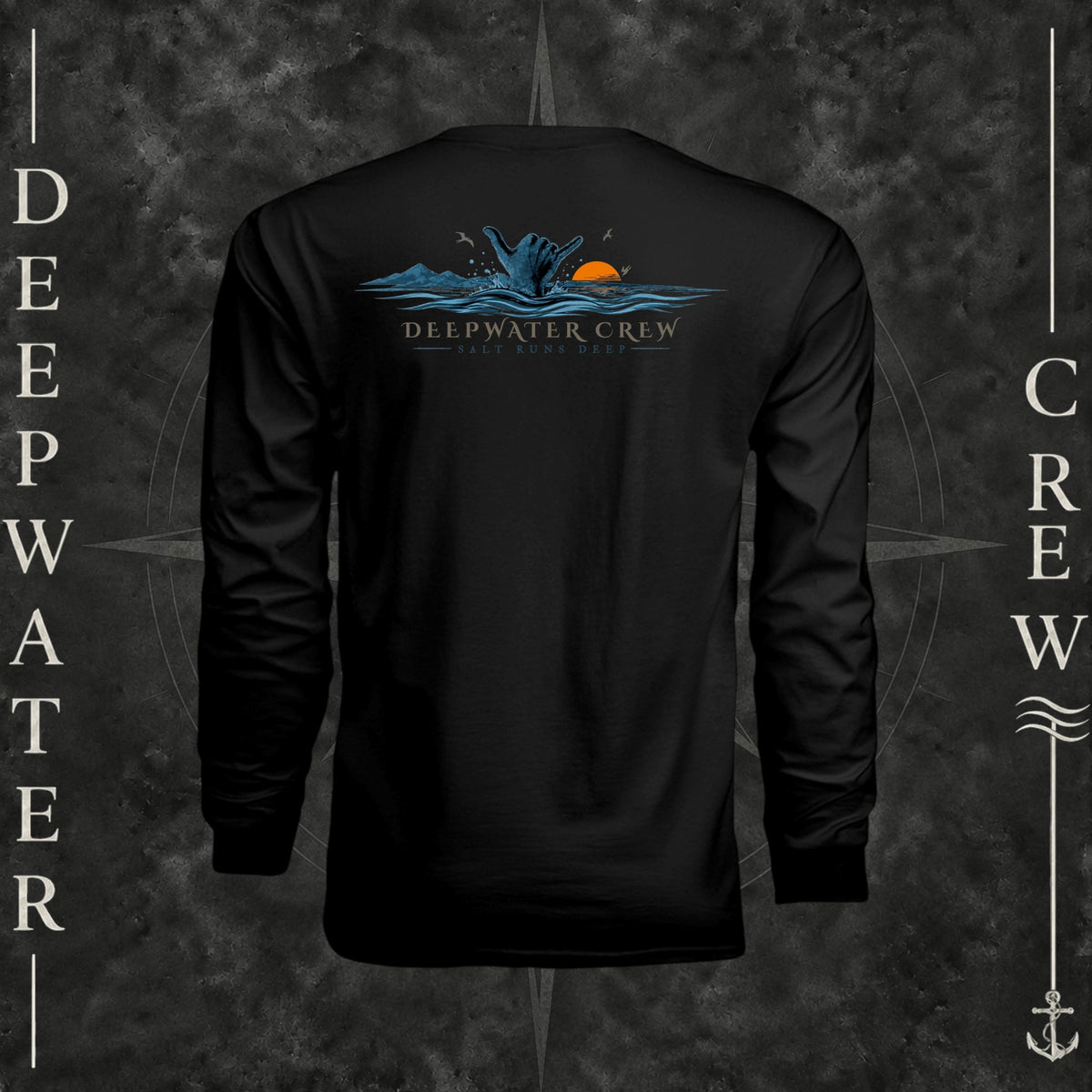 Black Deepwater Crew Co. Salt Runs Deep UPF 44+ long-sleeve performance shirt, back view with shaka hand, ocean waves, distant mountains, orange sunset, seabirds, and “Salt Runs Deep” lettering.