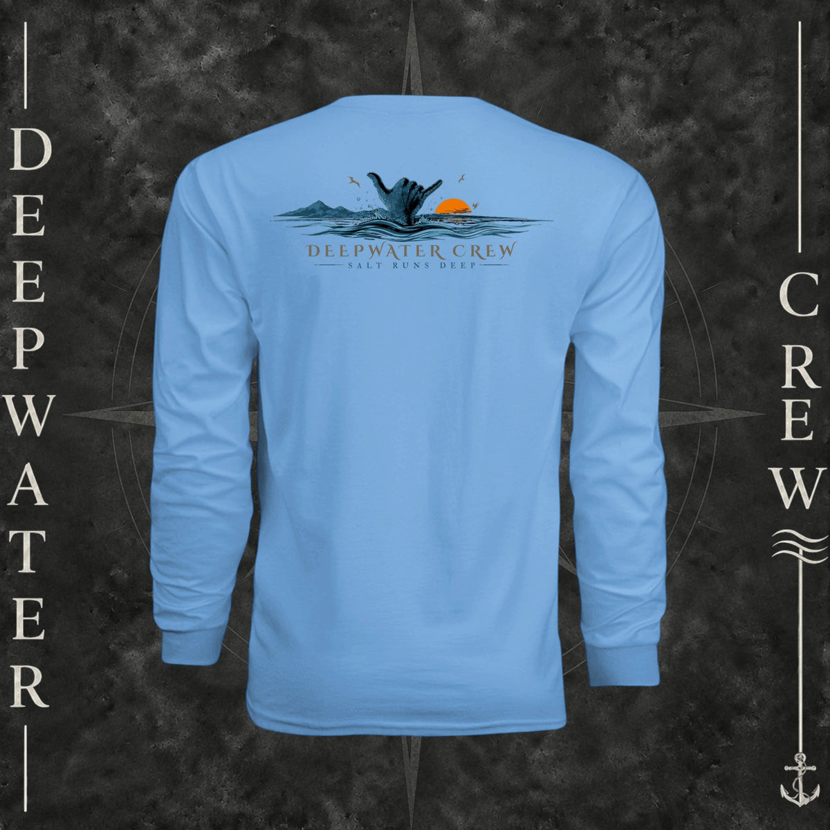 Light Blue Deepwater Crew Co. Salt Runs Deep UPF 44+ long-sleeve performance shirt, back view with shaka hand, ocean waves, distant mountains, orange sunset, seabirds, and “Salt Runs Deep” lettering.