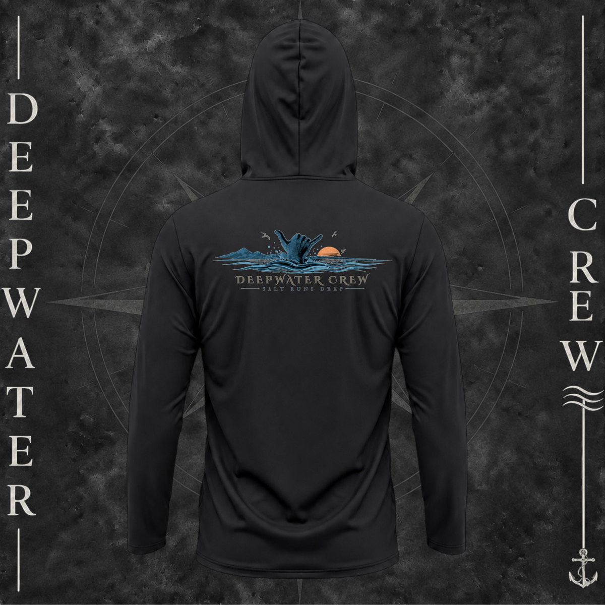 Black Deepwater Crew Co. Salt Runs Deep UPF 50+ performance hoodie, back view with shaka hand, ocean waves, distant mountains, orange sunset, seabirds, and “Salt Runs Deep” lettering.