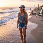 Deepwater Crew Co. trucker cap with DC wave logo worn by a woman walking on the beach at sunset