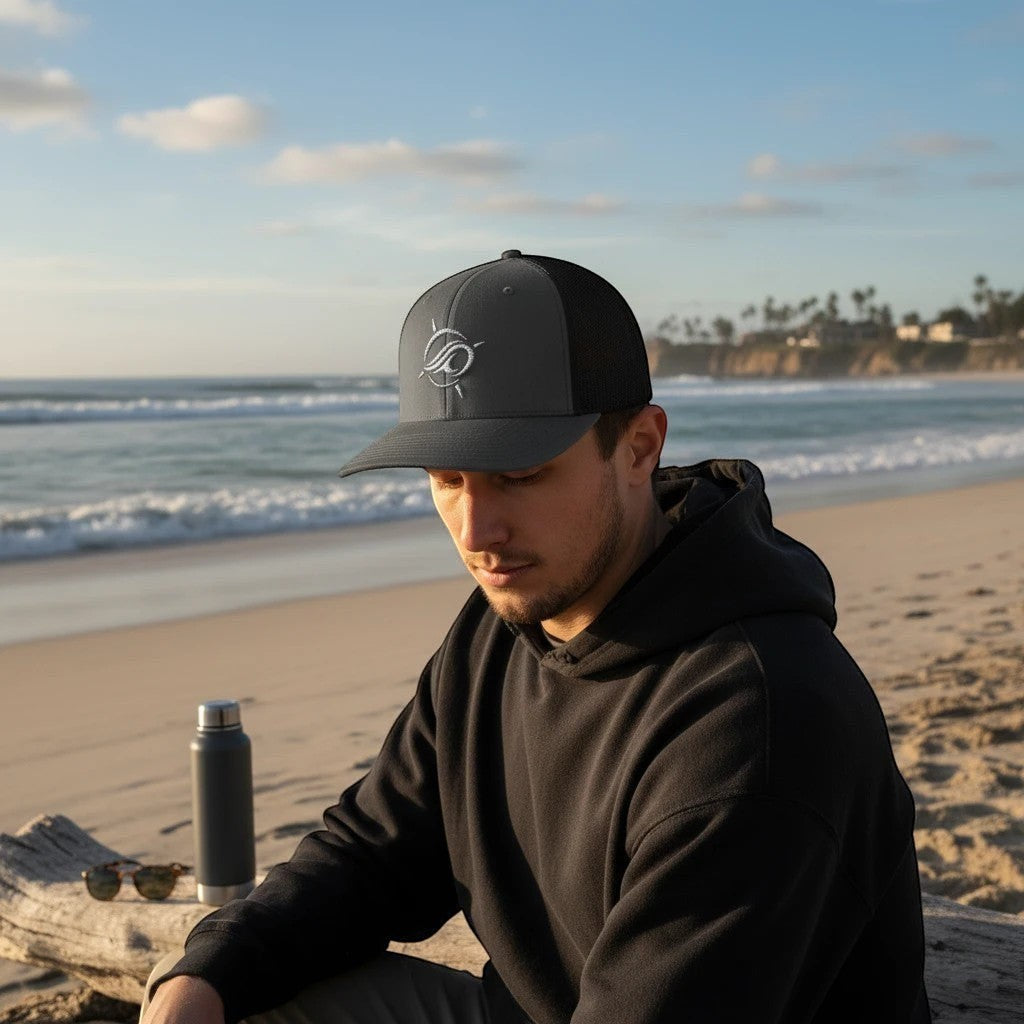 Deepwater Crew Co. dark grey and black trucker hat with embroidered wave logo, mesh back, and curved brim.