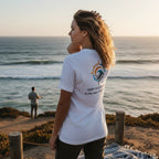 Woman wearing a white Deepwater Crew Co. cotton t-shirt with a nautical graphic on the back at the ocean shore.