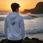 Deepwater Crew Co. white performance UPF hoodie with a nautical compass logo, worn by a man at sunset by the ocean.
