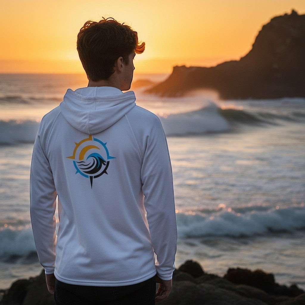 Deepwater Crew Co. white performance UPF hoodie with a nautical compass logo, worn by a man at sunset by the ocean.